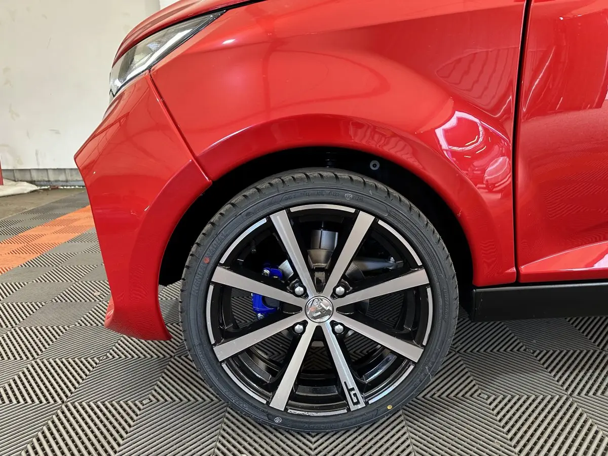 Gros plan sur la roue avant gauche rouge d'une Aixam Ambition 0.5 City Coupe GTI avec jante noire et détails gris.