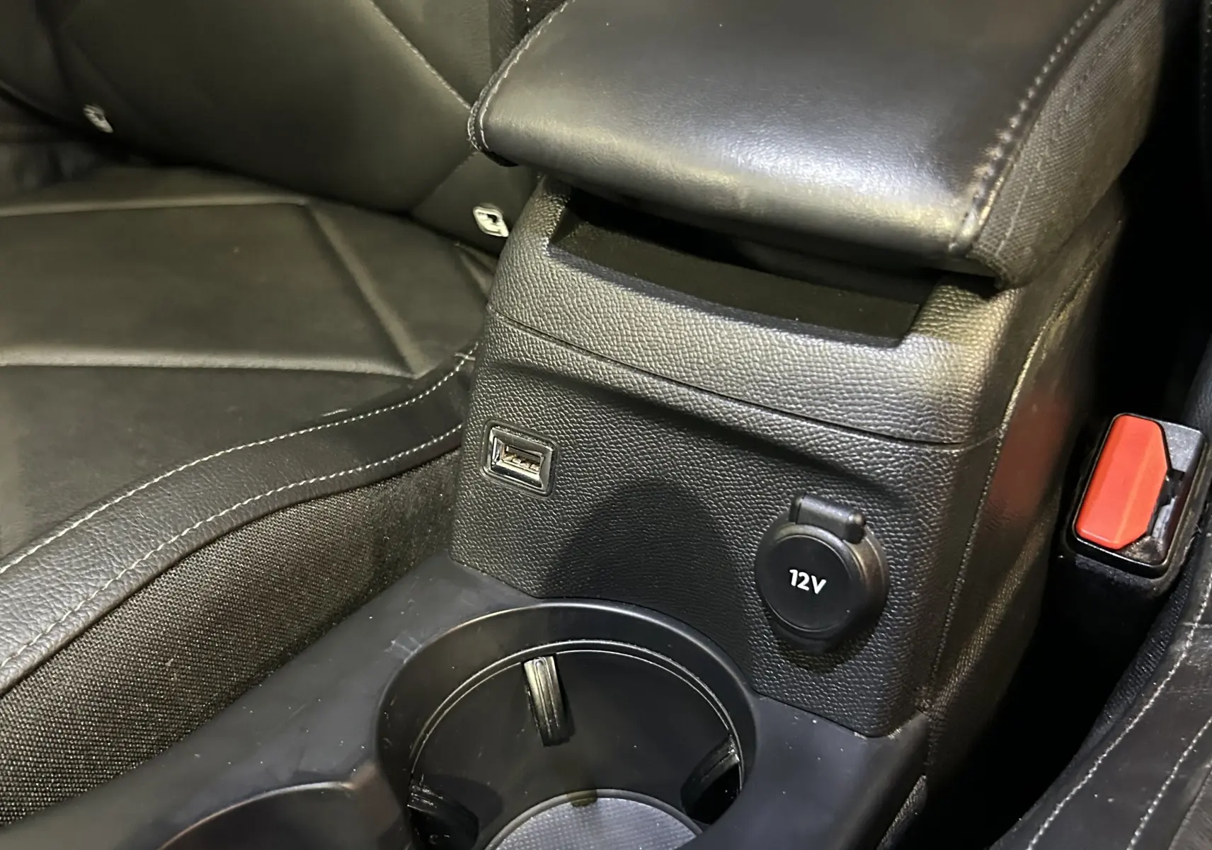 Gros plan sur la console centrale en cuir noir du DS3 Crossback avec prise USB et prise 12V visible.