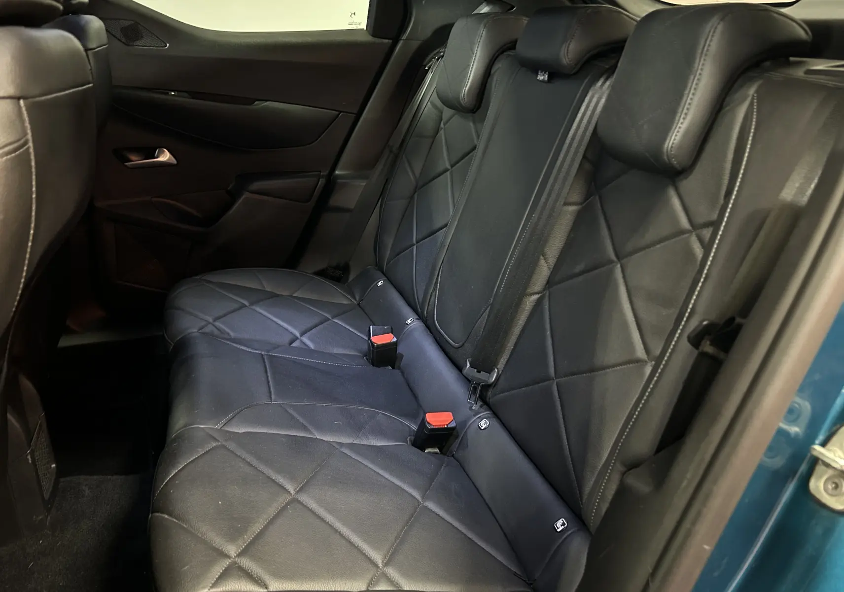 Vue intérieure côté droit des sièges arrière en cuir noir matelassé du DS3 Crossback Bleu Millenium, avec ceinture de sécurité visible.