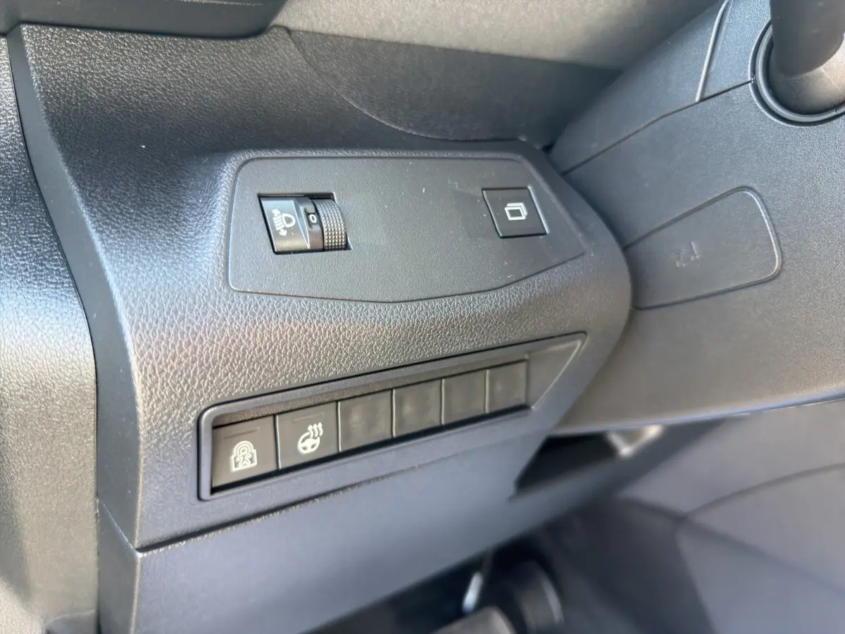 Détail intérieur côté conducteur du Peugeot Rifter bleu 2026 montrant les commandes de réglage des phares et sièges chauffants.