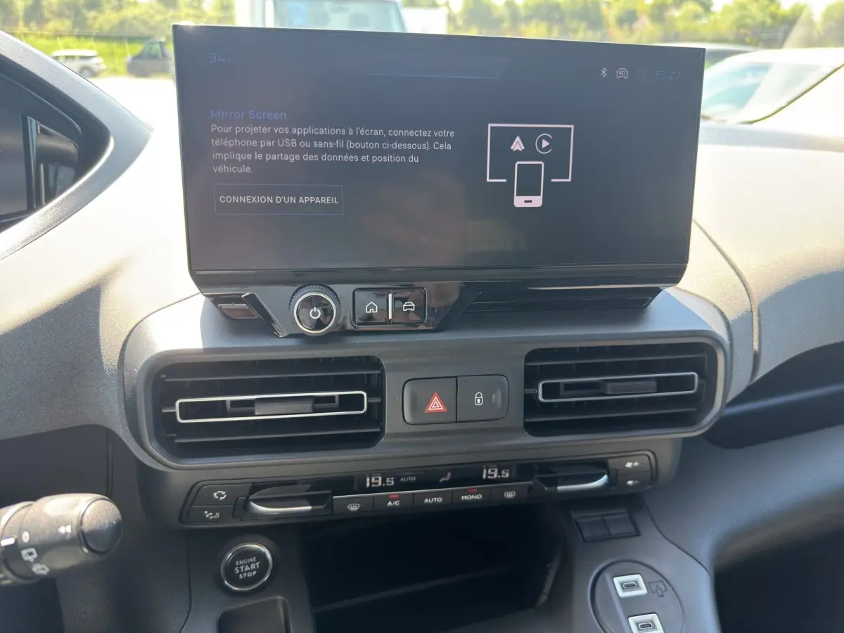 Vue rapprochée du tableau de bord du Peugeot Rifter 2026 avec écran tactile central et commandes de climatisation.