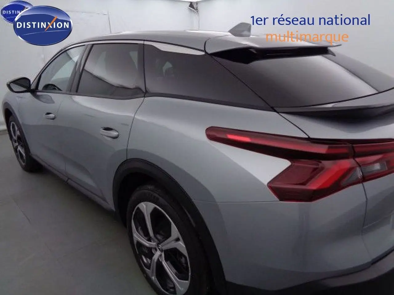 Vue 3/4 arrière côté gauche d'une Citroën C5 X gris Artense métallisé avec vitres teintées et feux arrière LED distinctifs.