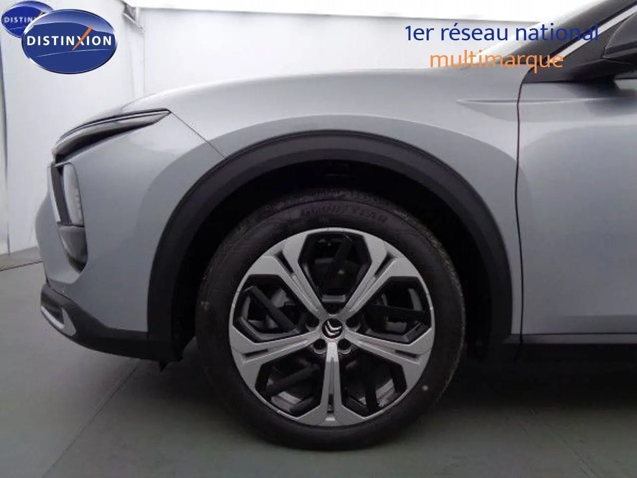 Gros plan sur la roue avant gauche et l'aile d'une Citroën C5 X gris Artense métal avec jante alliage distinctive.