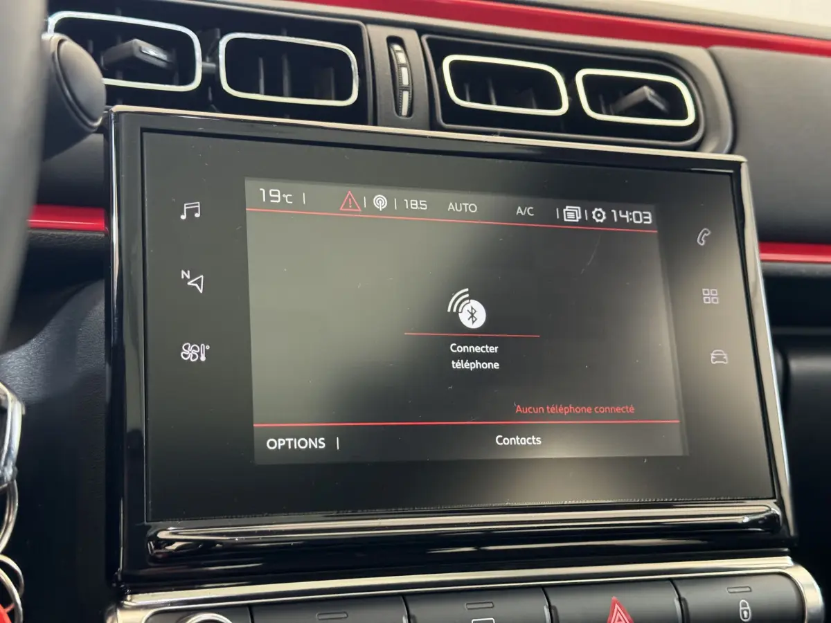 Écran tactile central en gros plan dans l'habitacle noir et rouge de la Citroën C3 PureTech 2019.
