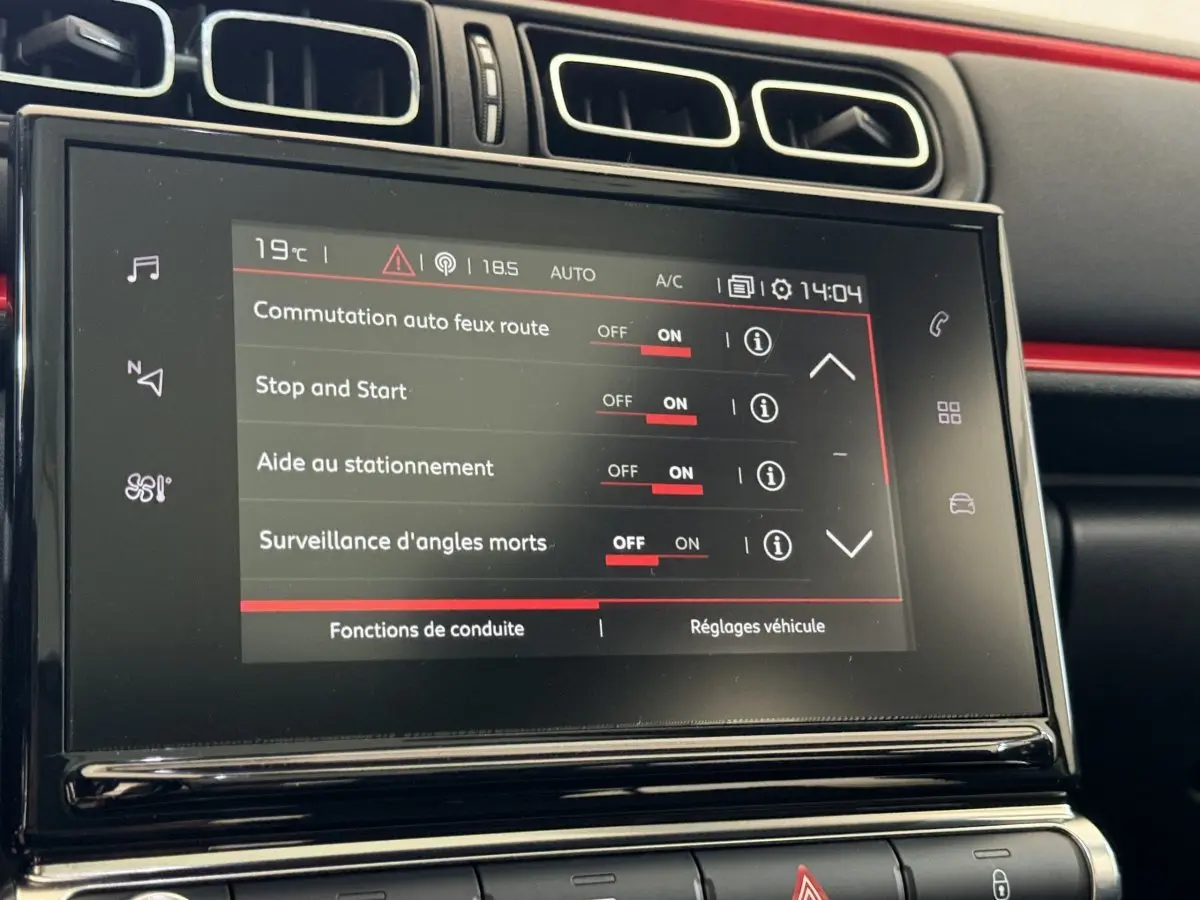 Écran tactile central affichant les réglages d'aide à la conduite dans l'habitacle noir et rouge d'une Citroën C3 2019.