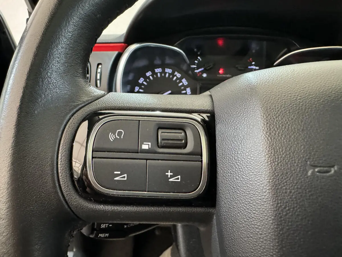 Gros plan sur les commandes gauche du volant cuir noir d'une Citroën C3 2019 PureTech Shine Business.