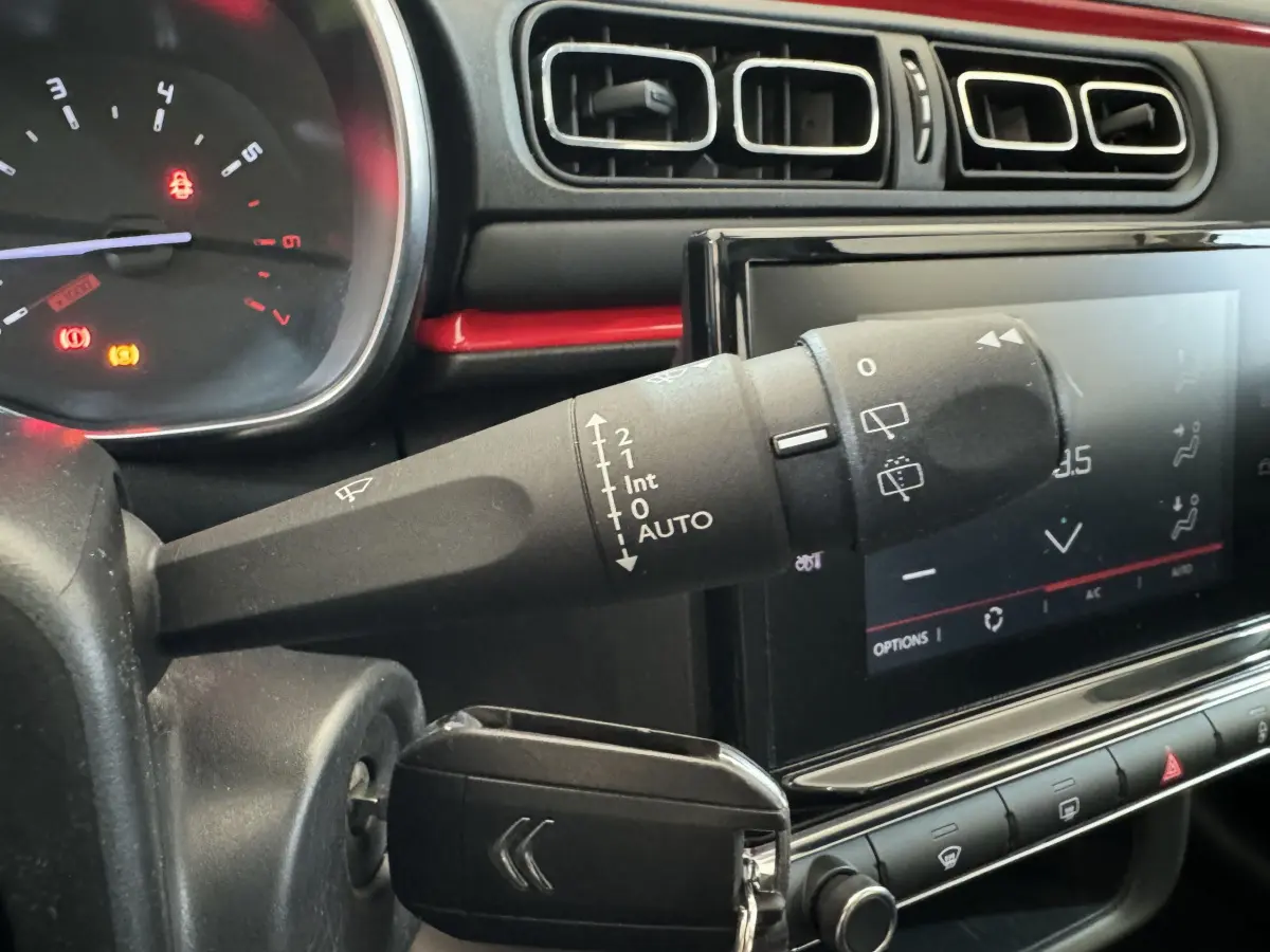 Gros plan sur la commande d’essuie-glace et l’écran tactile du tableau de bord noir d’une Citroën C3 2019 Shine Business.