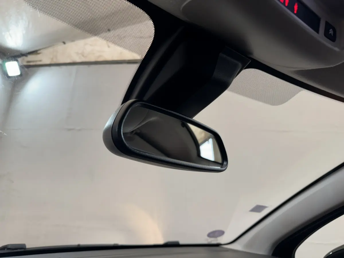Vue intérieure rapprochée du rétroviseur central d’une Citroën C3 noire, 2019, avec pare-brise et ciel de toit visibles.