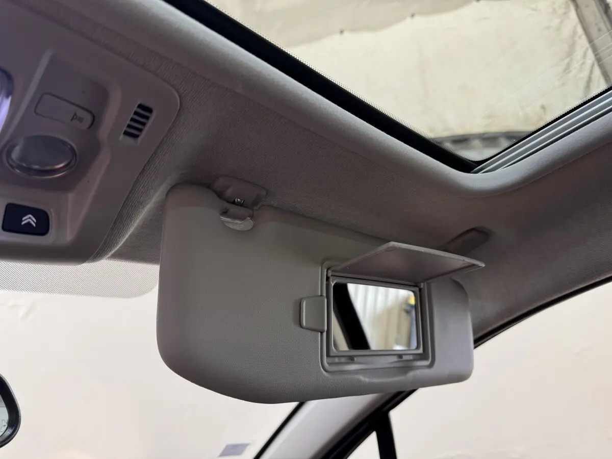 Détail intérieur montrant le pare-soleil avec miroir ouvert et toit ouvrant du Citroën C3 noir, version Shine Business.