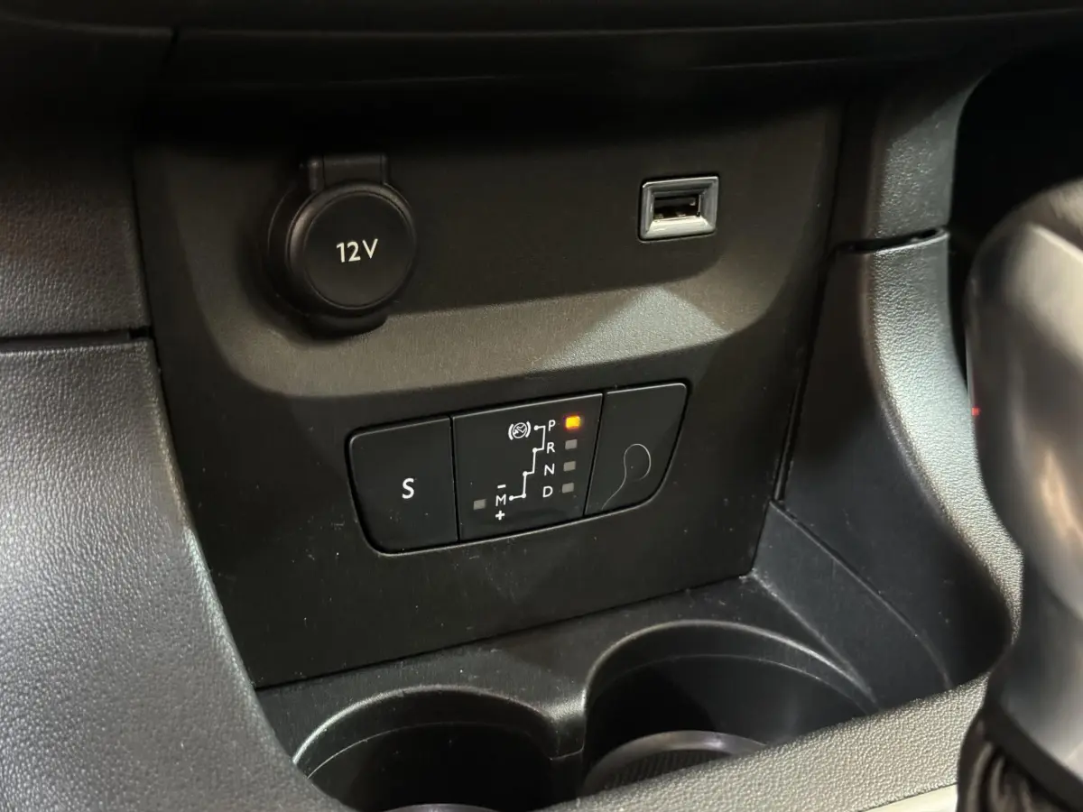 Gros plan sur la console centrale de la Citroën C3 noire, montrant la commande de boîte automatique et prise 12V.
