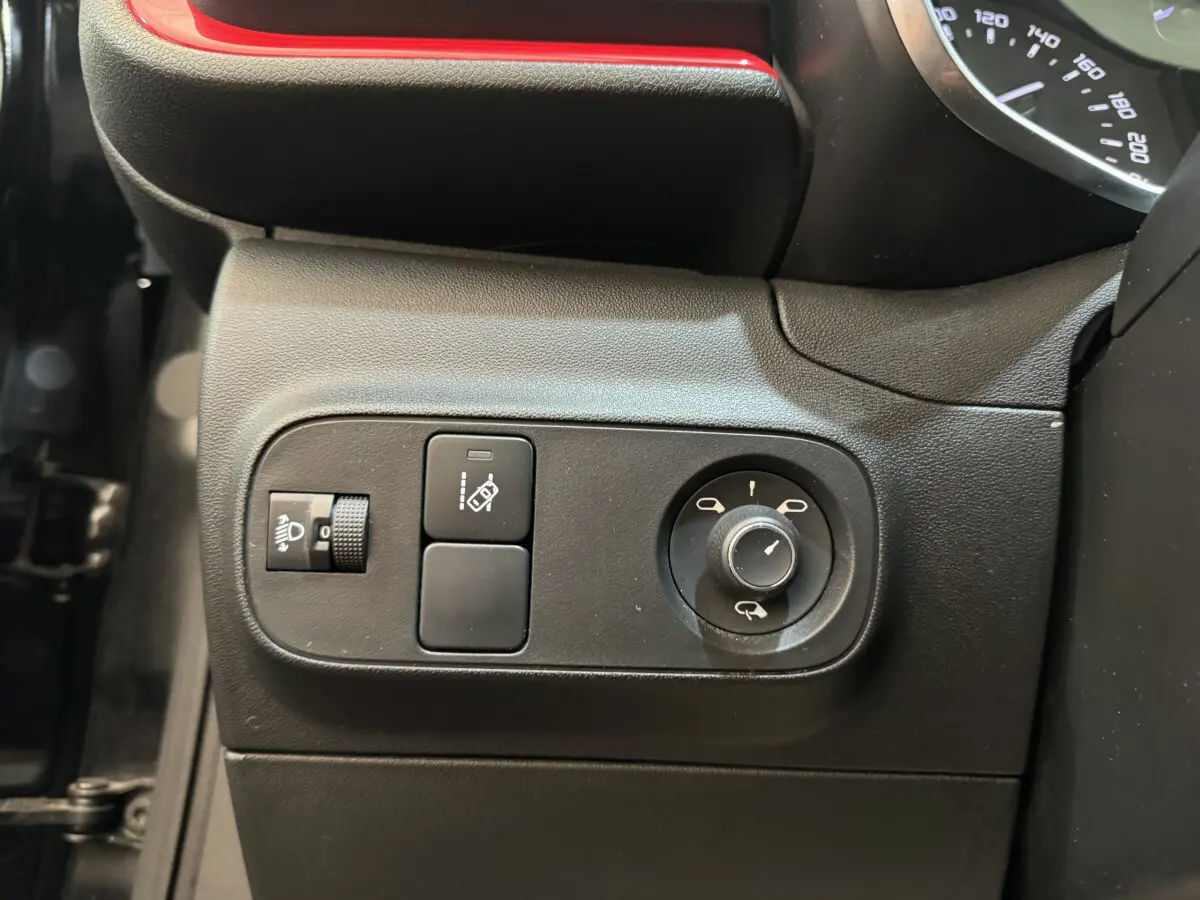 Gros plan sur les commandes de réglage des rétroviseurs et des phares côté gauche d'une Citroën C3 noire de 2019.