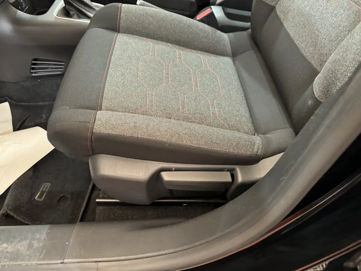 Gros plan sur le siège avant droit gris avec surpiqûres rouges de la Citroën C3 PureTech 110 noire de 2019.