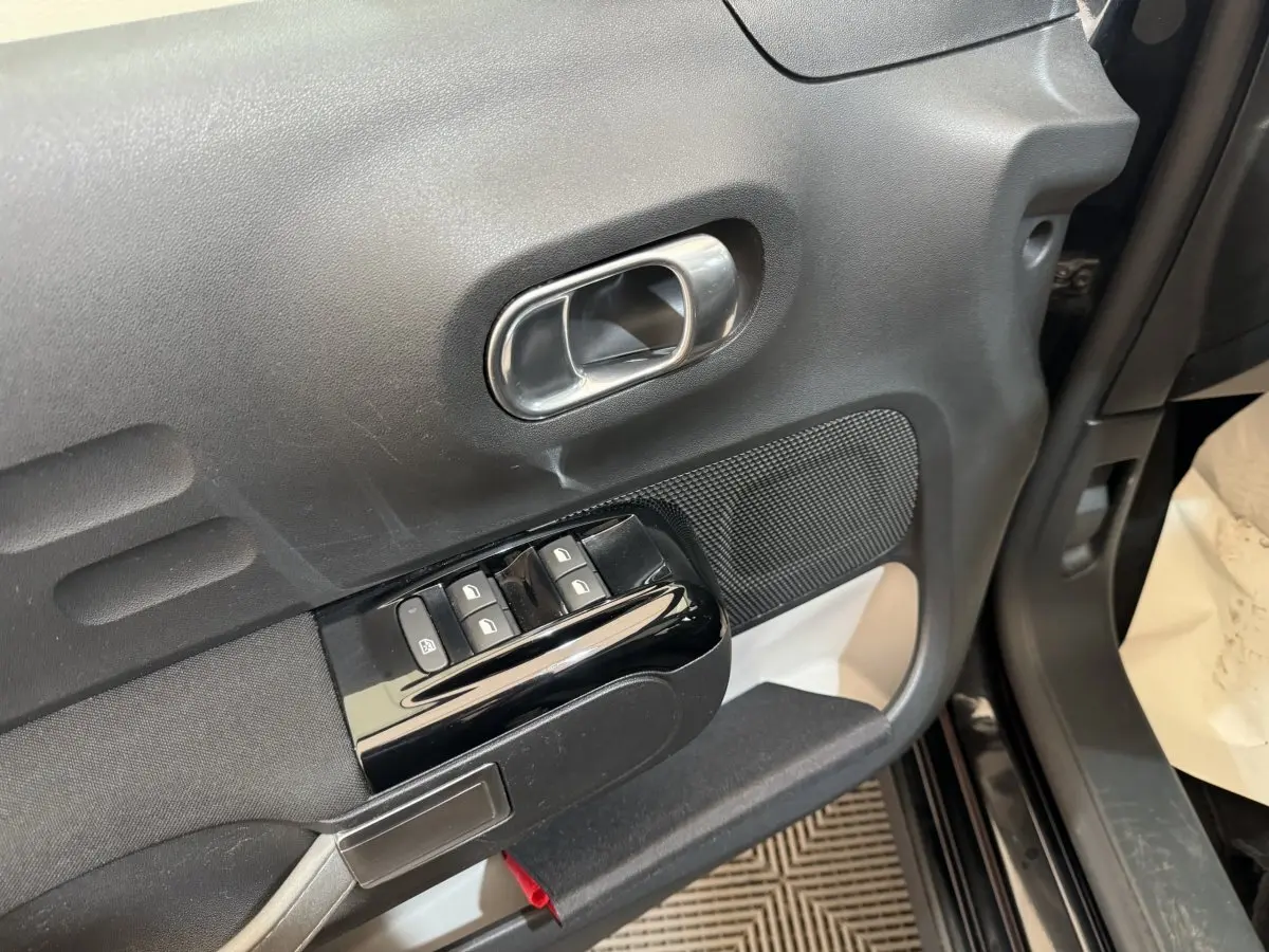 Poignée de porte intérieure côté conducteur de Citroën C3 noire, avec commandes de vitres et verrouillage.