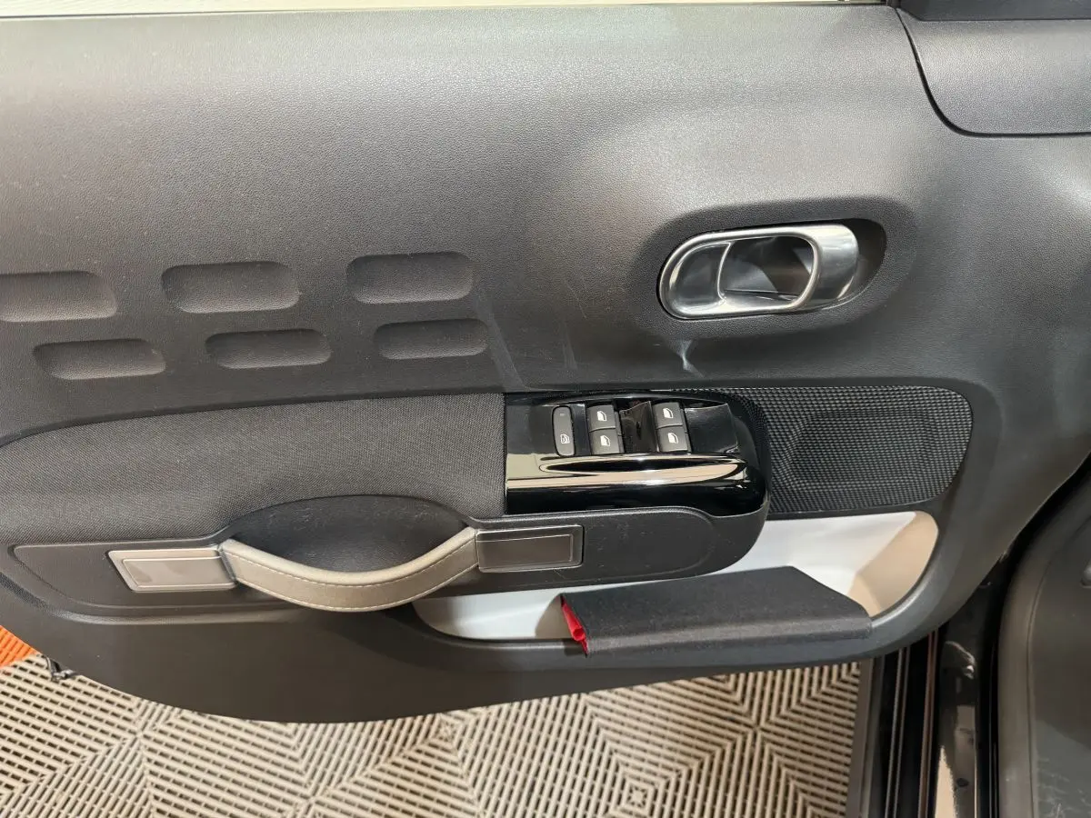 Vue rapprochée de la porte avant gauche noire d'une Citroën C3 2019, avec commandes de vitres et poignée intégrée.