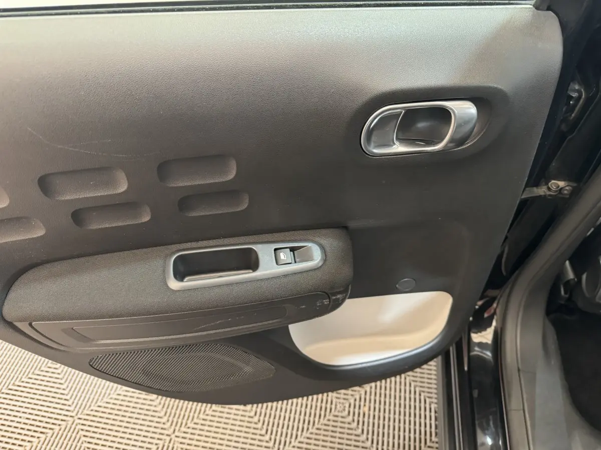 Vue rapprochée de la porte arrière gauche noire de la Citroën C3 avec poignée argentée et commande de fenêtre.
