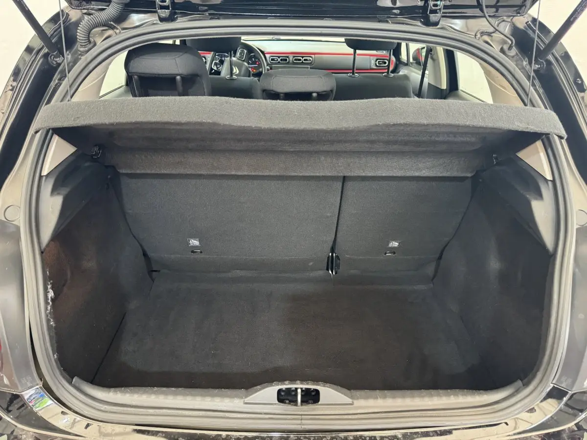 Coffre ouvert d'une Citroën C3 noire vue de l'arrière, montrant l'espace de chargement et la tablette cache-bagages relevée.