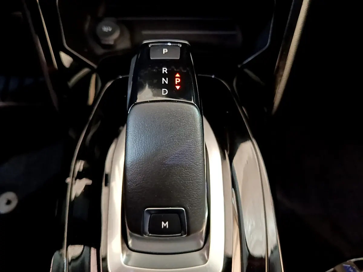 Le levier de vitesses automatique noir du Peugeot 2008 PureTech 130 vu de dessus dans un intérieur sombre.