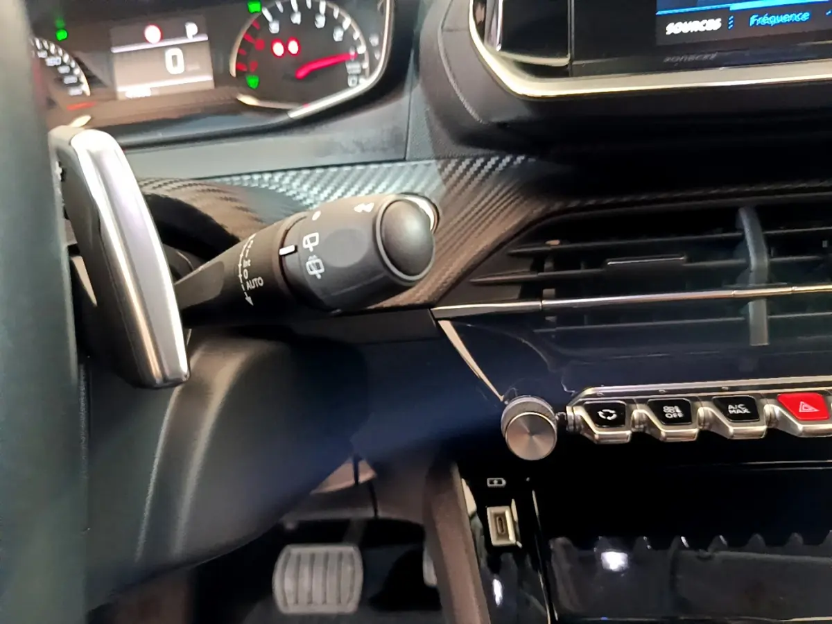 Gros plan intérieur sur le tableau de bord et commandes du Peugeot 2008 gris foncé, avec volant et écran tactile visibles.