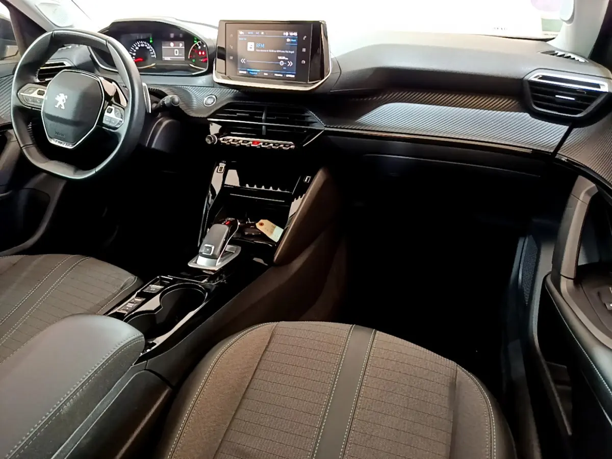Vue intérieure côté conducteur de la Peugeot 2008 2022, tableau de bord noir avec écran tactile et volant compact cuir.