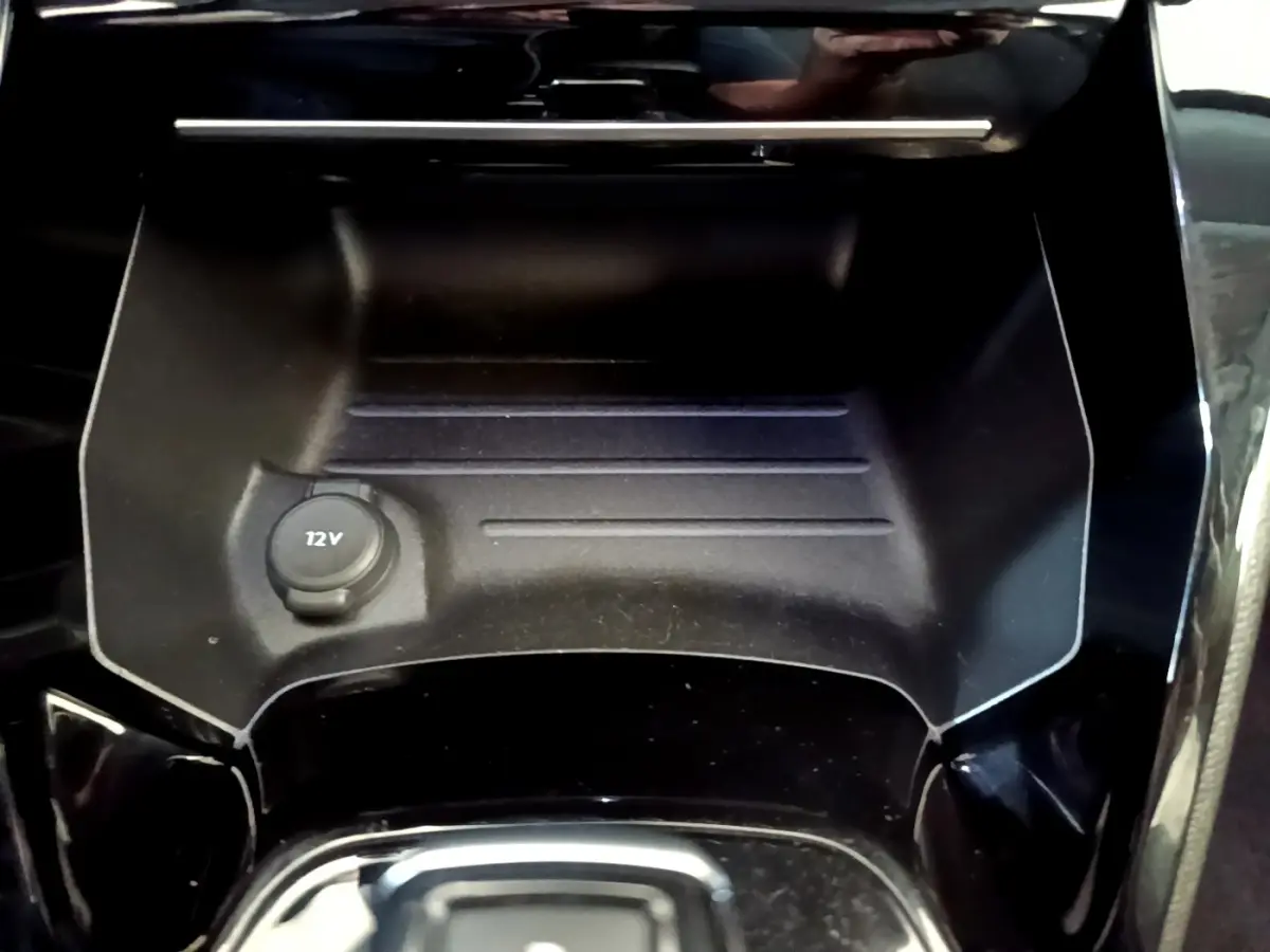 Gros plan sur la prise 12V dans le rangement central noir brillant de la Peugeot 2008 gris foncé, version Allure 2022.