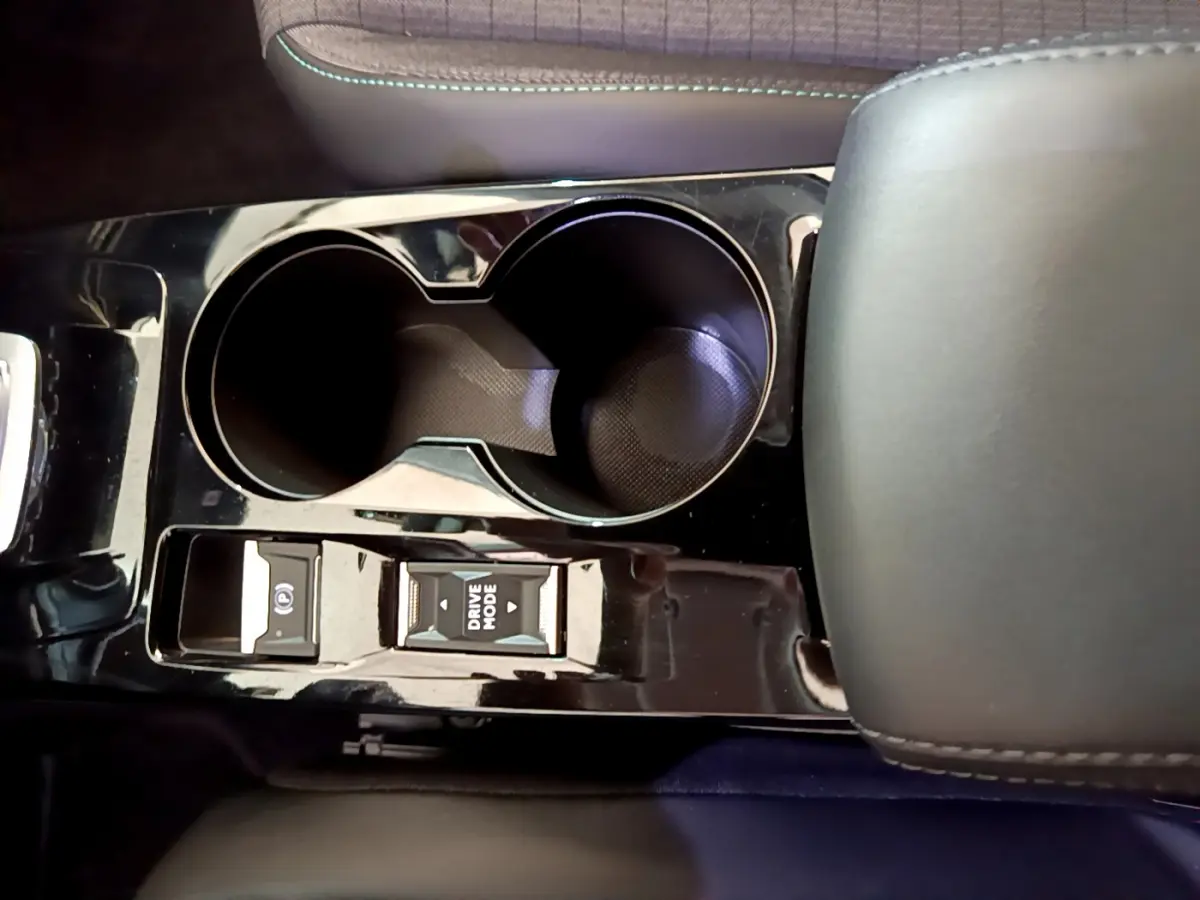 Vue rapprochée de la console centrale noire brillante du Peugeot 2008 avec porte-gobelets et commandes Drive Mode.