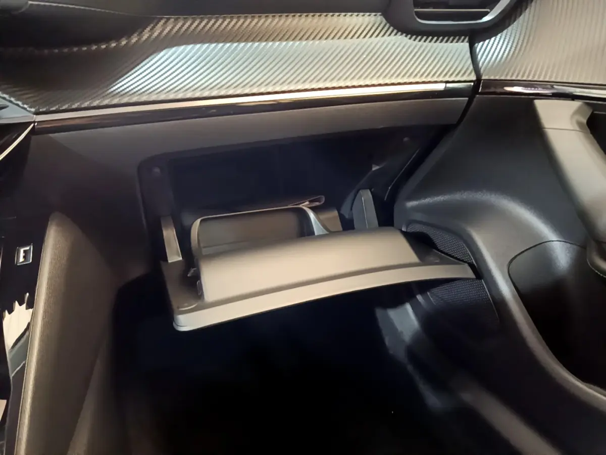 Vue intérieure du coffre à gants ouvert sur le côté passager d’un Peugeot 2008 gris foncé, avec tableau de bord texturé.
