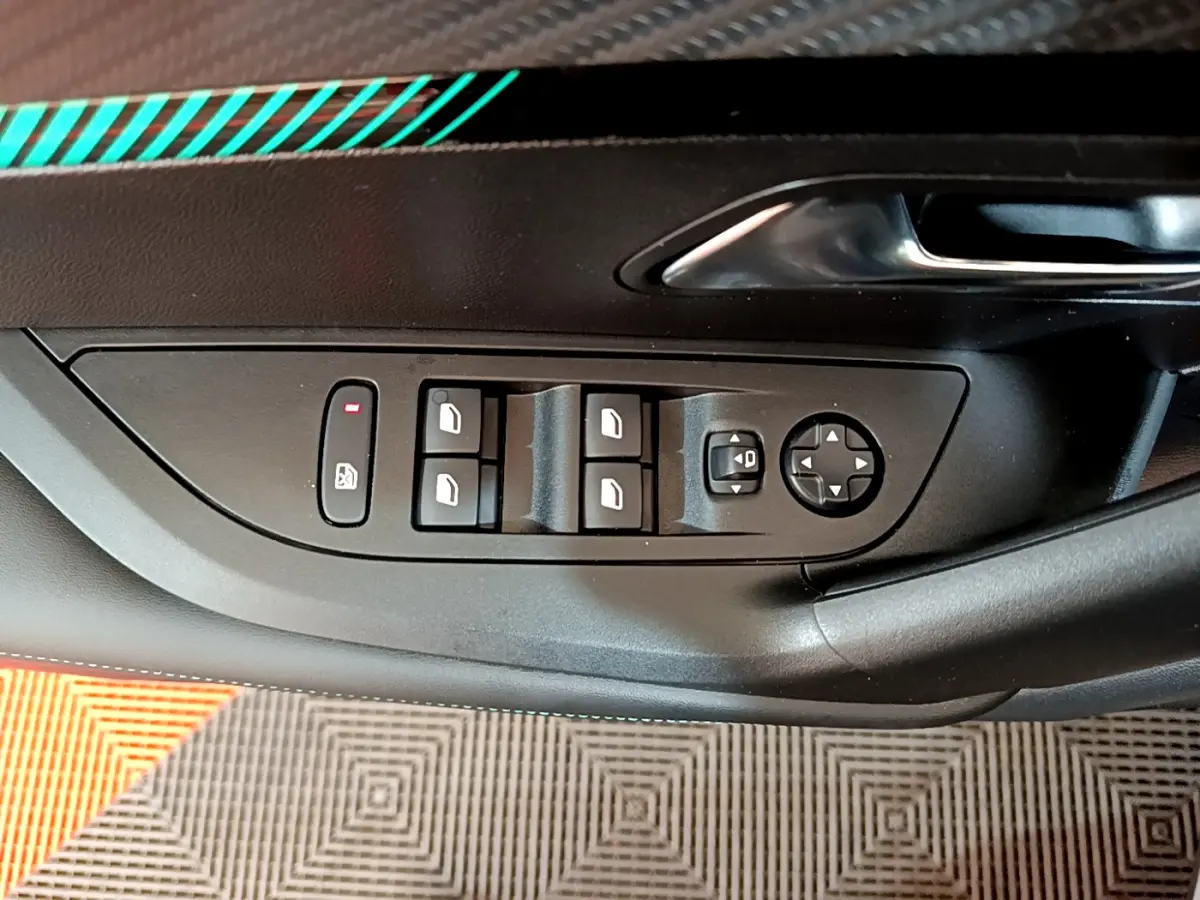 Vue rapprochée des commandes de lève-vitres et réglages des rétroviseurs sur la porte côté conducteur d’une Peugeot 2008 gris foncé.