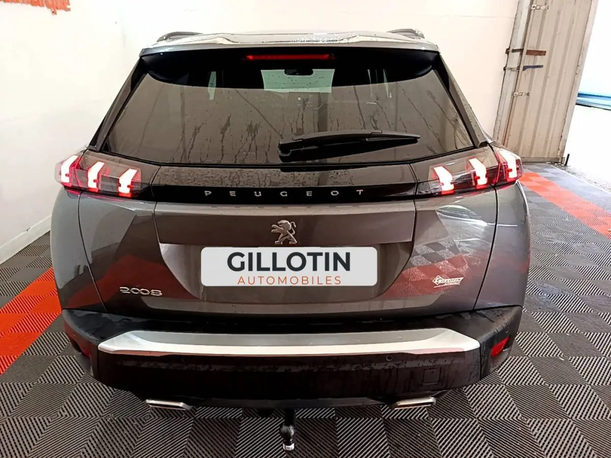 Vue arrière d’un Peugeot 2008 gris foncé avec feux LED allumés et attelage visible en intérieur d’exposition.