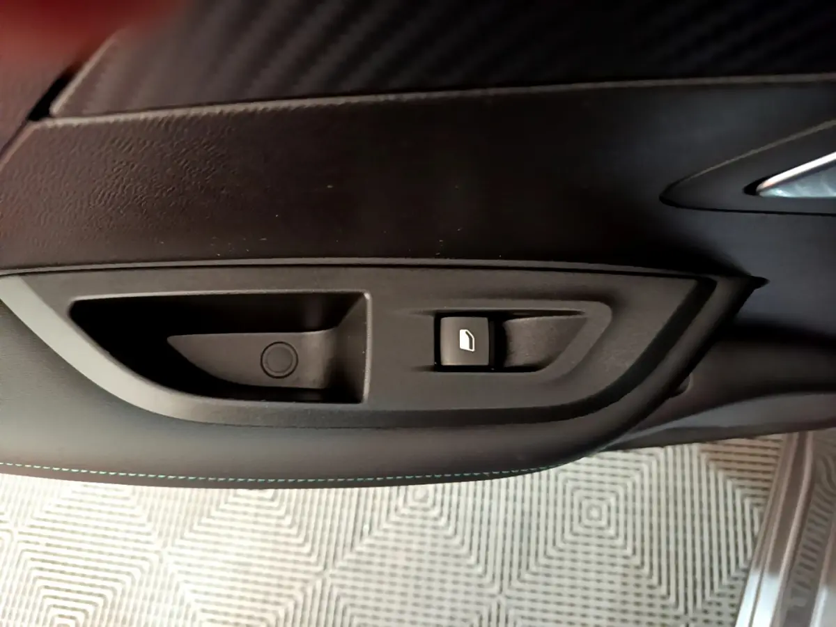 Gros plan sur la commande d’ouverture de trappe à carburant noire dans l’habitacle du Peugeot 2008 gris foncé.