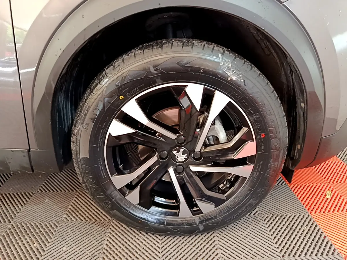 Gros plan sur la roue avant droite du Peugeot 2008 gris foncé avec jante alliage noire et argentée.