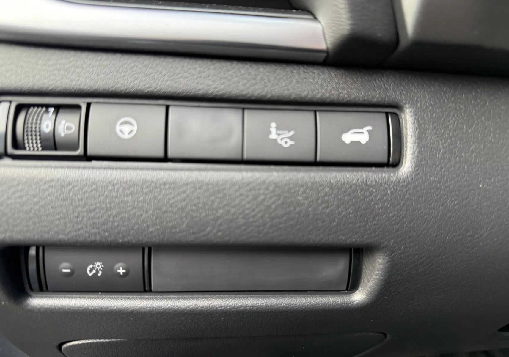 Gros plan sur les boutons de commande intérieurs noirs du Nissan Qashqai 1.5 E-POWER gris, avec icônes blanches lumineuses.