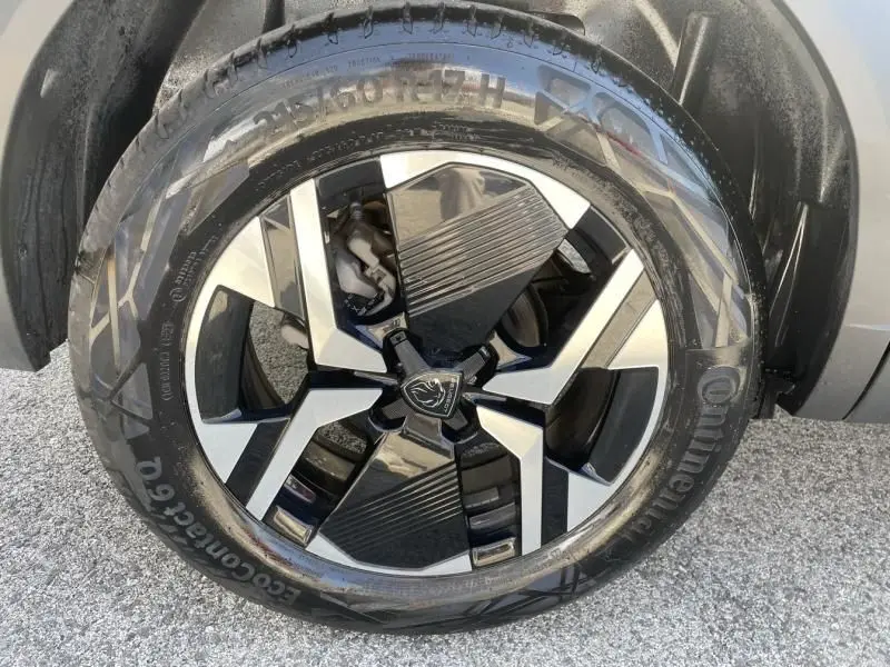 Gros plan sur la roue avant droite du Peugeot 2008 gris métal 2025, avec jante alliage noire et argentée au design moderne.