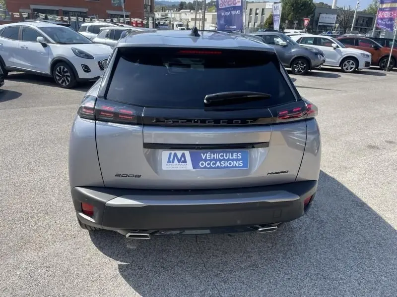 Vue arrière d’un Peugeot 2008 gris métal 2025 avec feux LED et logo Peugeot noir brillant sur un parking.