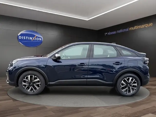 Vue de profil côté gauche d'une Citroën C4 hybride 145 e-DSC6 bleu avec jantes alliage en intérieur showroom.