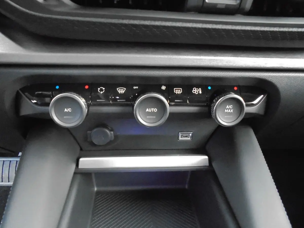 Commandes de climatisation automatique avec trois boutons rotatifs et port USB sur la console centrale d'une Citroën C5 X blanche nacrée.