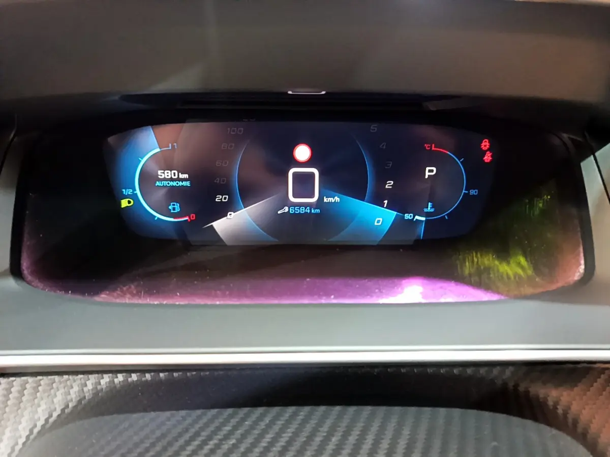 Affichage numérique du tableau de bord de la Peugeot 208 gris foncé, montrant vitesse, autonomie et température moteur.