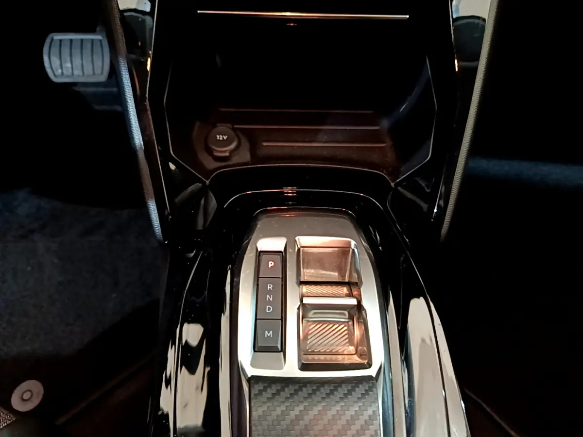 Vue plongeante sur la console centrale noire brillante de la Peugeot 208 PureTech 100 avec sélecteur de boîte auto et bouton P.