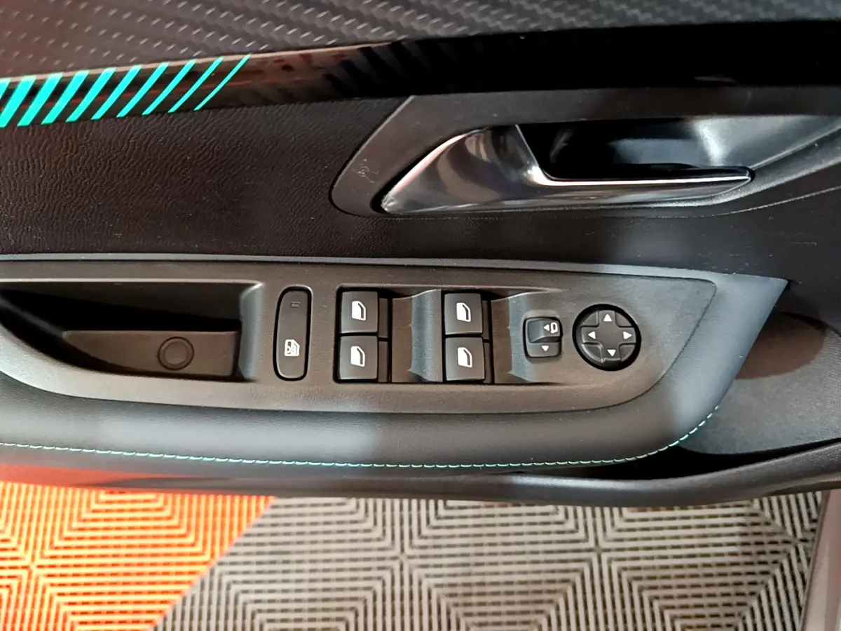 Vue rapprochée de la porte côté conducteur d’une Peugeot 208 gris foncé, avec commandes électriques des vitres et rétroviseurs.