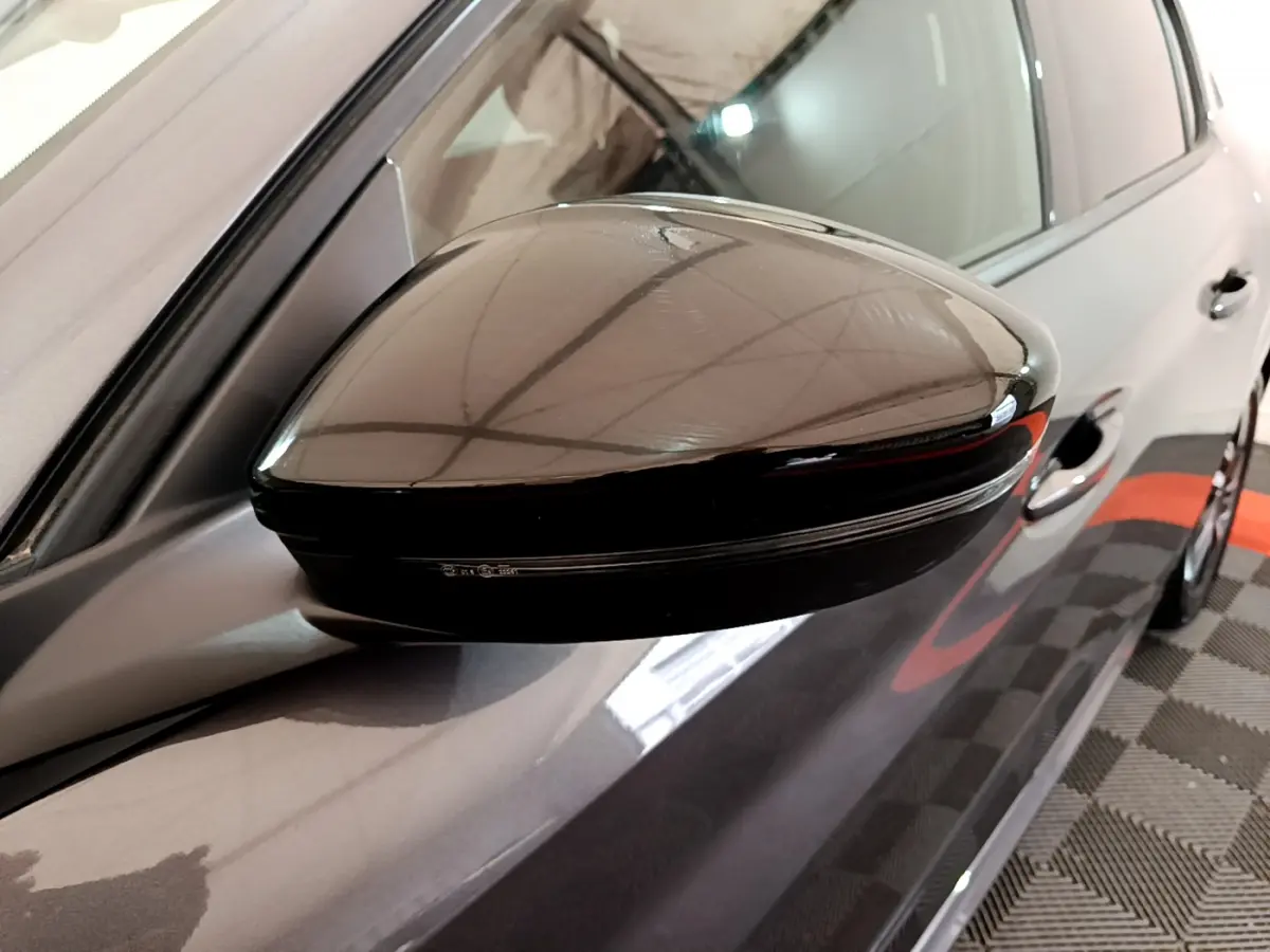 Gros plan sur le rétroviseur noir côté gauche d’une Peugeot 208 gris foncé vue de profil.