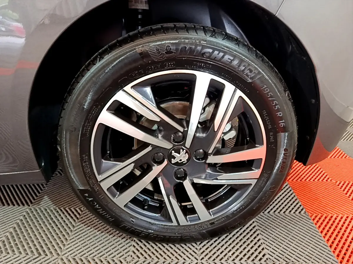 Gros plan sur la roue avant droite gris foncé d'une Peugeot 208 PureTech 100 avec jante alliage bicolore.