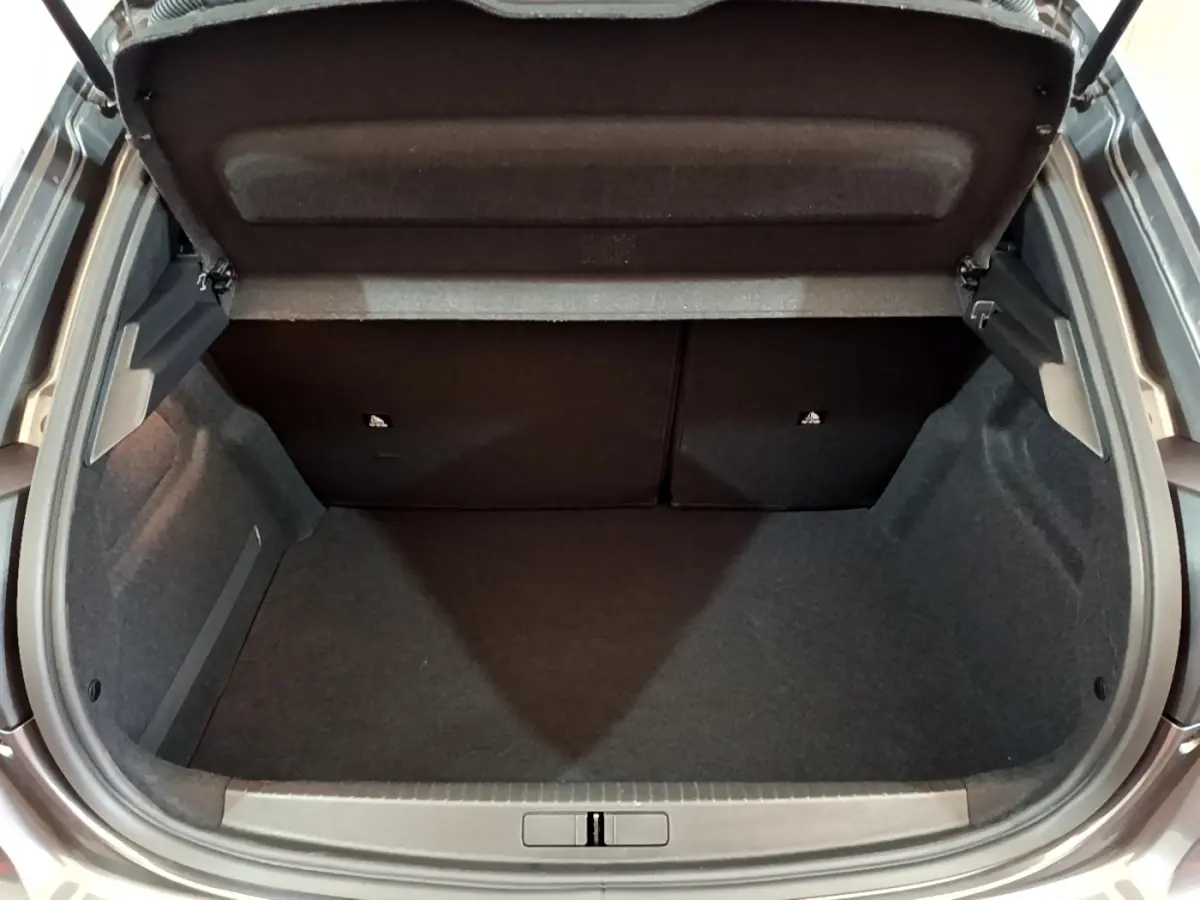 Coffre ouvert vu de dessus d'une Peugeot 208 gris foncé, montrant l'espace de rangement intérieur vide.