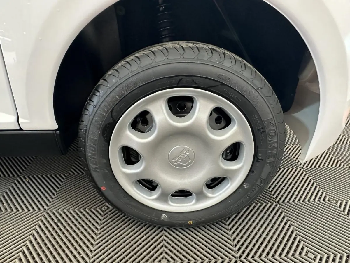 Gros plan sur la roue avant droite d'une Aixam Minauto E Access blanche, montrant le pneu Kenda et l'aile du véhicule.