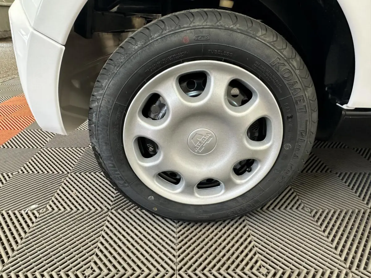 Gros plan sur la roue arrière droite blanche d'une Aixam Minauto E Access 2025 électrique sur sol texturé.