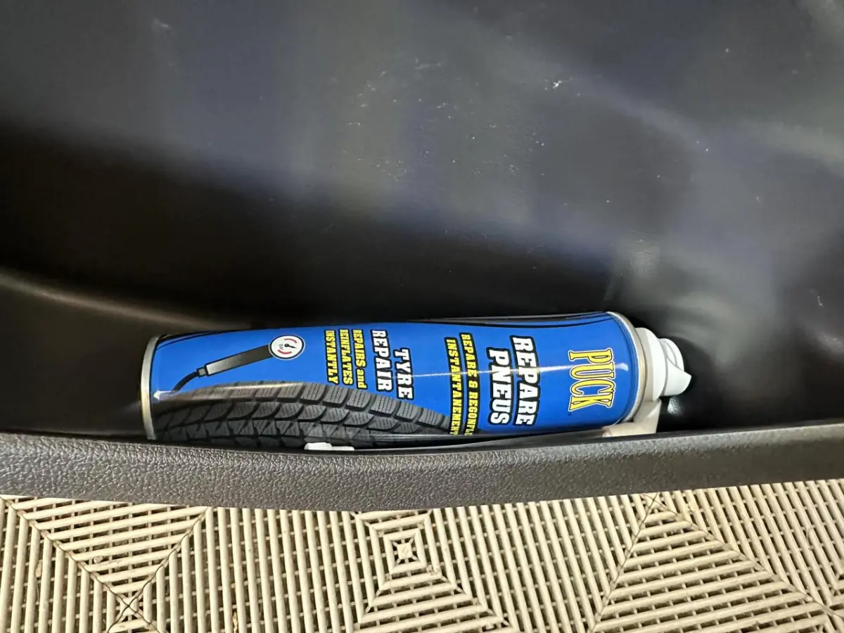 Gros plan sur une bombe de réparation de pneus bleue dans le rangement côté conducteur d'une Aixam Minauto E Access blanche.