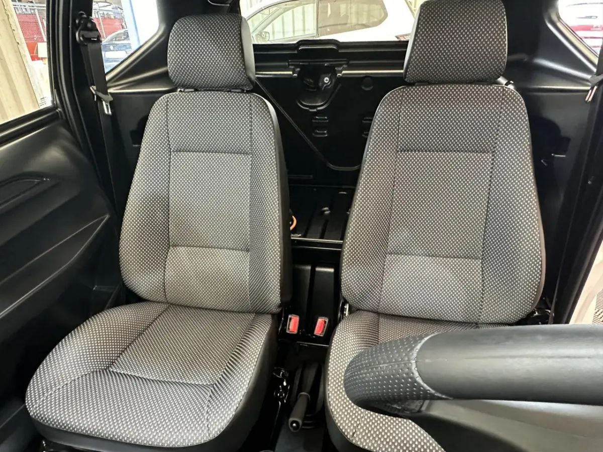 Vue intérieure rapprochée des sièges avant gris à motifs de l'AIXAM MINAUTO E ACCESS 2025, côté conducteur visible.