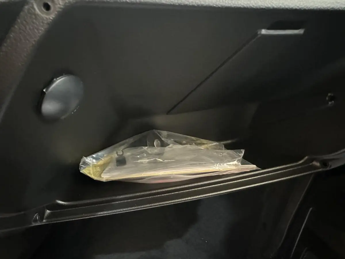 Gros plan sur la boîte à gants noire de l'AIXAM MINAUTO E ACCESS 2025 avec documents emballés à l'intérieur.