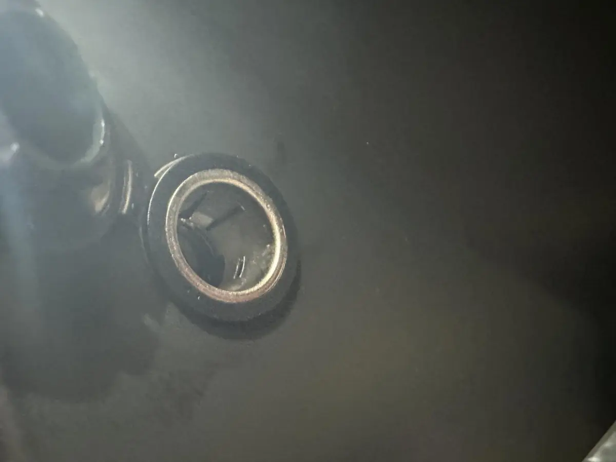 Gros plan sur la prise de recharge électrique du côté conducteur de l'AIXAM MINAUTO E ACCESS blanc 2025.