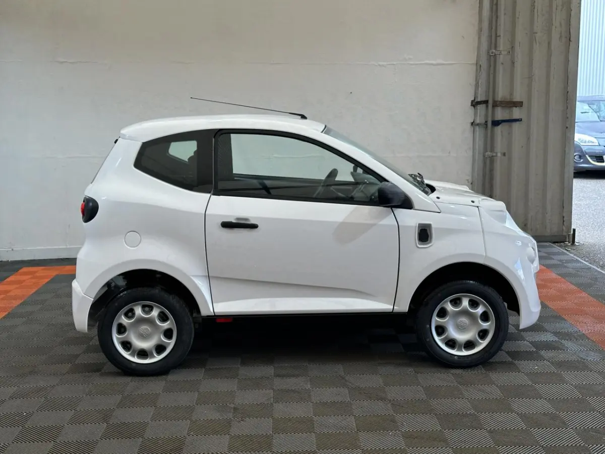 Profil droit d'une microcar AIXAM MINAUTO E ACCESS blanche de 2025 avec rétroviseur caméra côté conducteur.