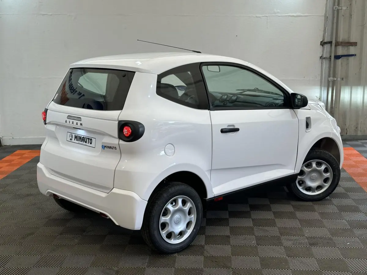 Vue 3/4 arrière droite d'une Aixam MINAUTO E ACCESS blanche 2025 avec rétroviseur caméra côté conducteur.