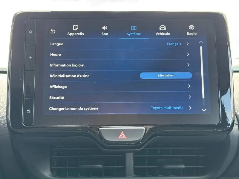 Écran tactile central du Toyota Yaris 116h Dynamic 2025 affichant le menu système en intérieur noir et gris.